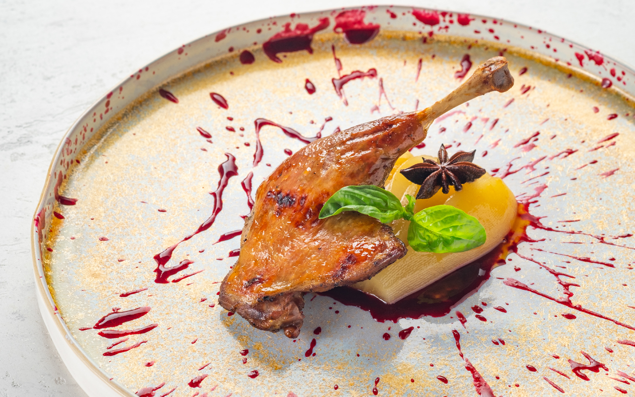 Crispy duck leg served over tangy pear in anise syrup and sweet chokeberry and raspberry sauce