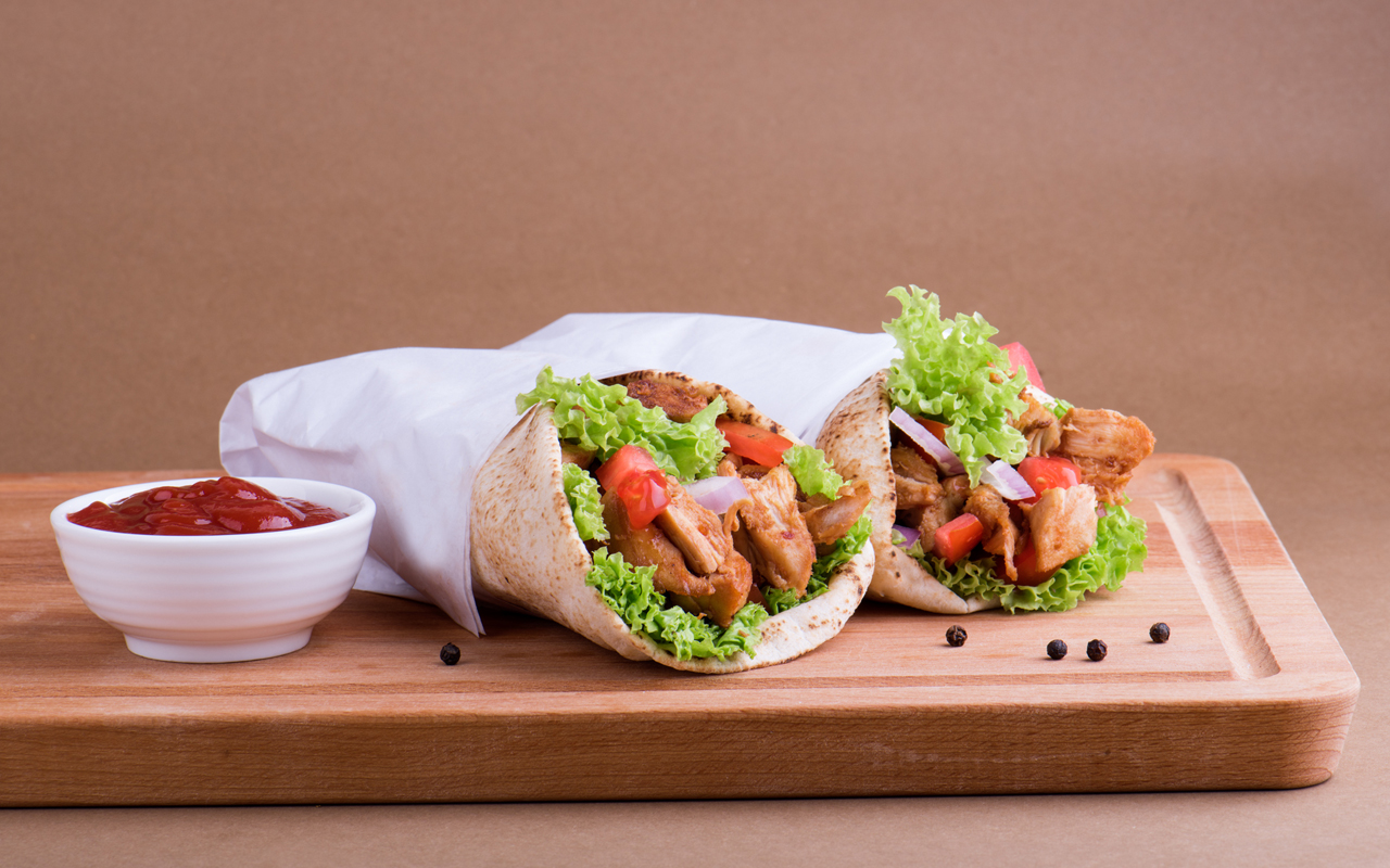 Juicy Shawarma-style chicken roll with garlic sauce, pickled vegetables and red cabbage salad, served on soft pita bread